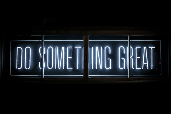 Image Description – a photo of a sign saying Do Something Great in illuminated neon text on a dark background. The sign is split into four panels.